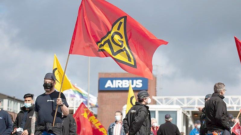 Beschäftigte des Airbus-Werkes in Finkenwerder schwenken Fahnen der IG Metall (Mai). Foto: Daniel Reinhardt/dpa