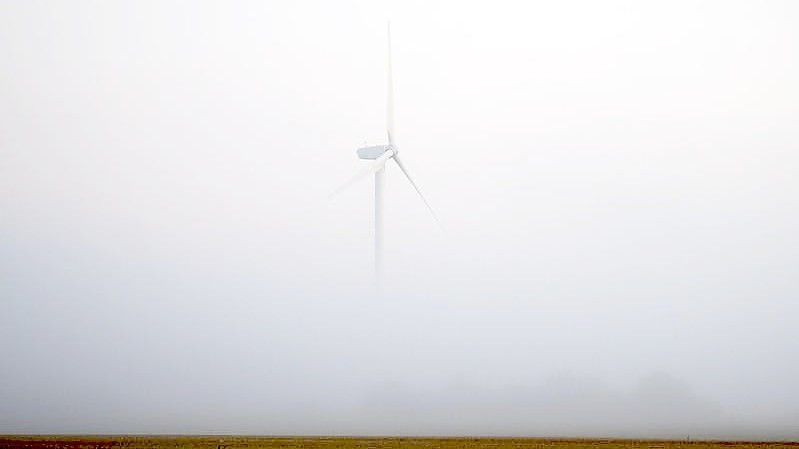 Ein Windrad ragt bei Hannover aus dem morgendlichen Nebel. Foto: Julian Stratenschulte/dpa