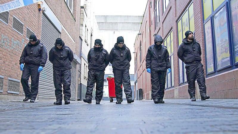 Polizisten führen eine Durchsuchung in der Nähe des Tatorts im Stadtzentrum durch, nachdem ein 12-jähriges Mädchen an den Folgen eines Angriffs gestorben ist. Foto: Peter Byrne/PA Wire/dpa