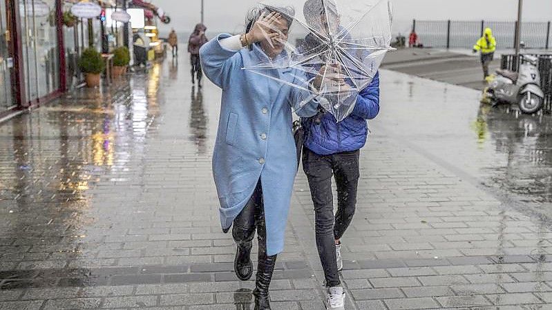 Ein Paar schützt sich mit einem Regenschirm vor starkem Wind und Regen in Istanbul. Foto: Uncredited/AP/dpa