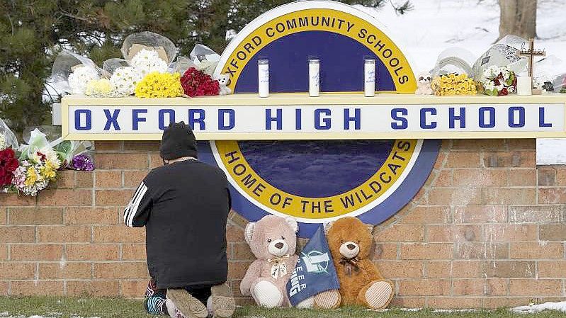 Eine Frau kniet zum Gebet vor dem Schild der Oxford High School im US-Bundesstaat Michigan. Ein 15-Jähriger hat dort mindestens vier seiner Mitschüler getötet. Foto: Paul Sancya/AP/dpa