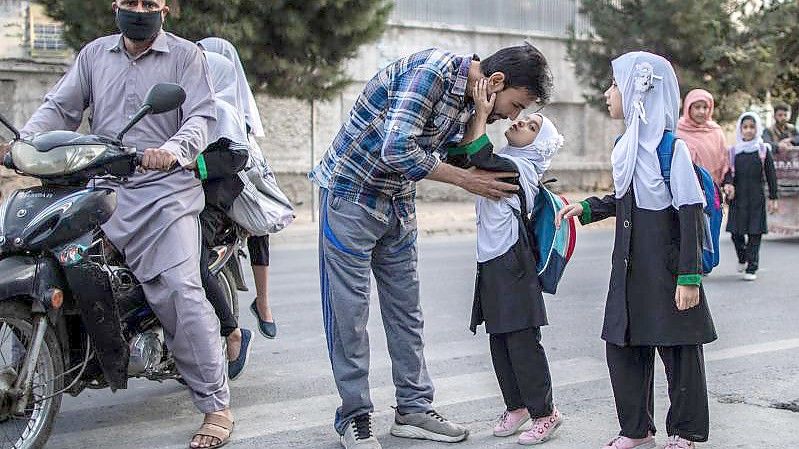 Ein junges afghanisches Mädchen gibt ihrem Vater einen Kuss, bevor sie eine Grundschule in Kabul besucht. (Archivbild). Foto: Oliver Weiken/dpa