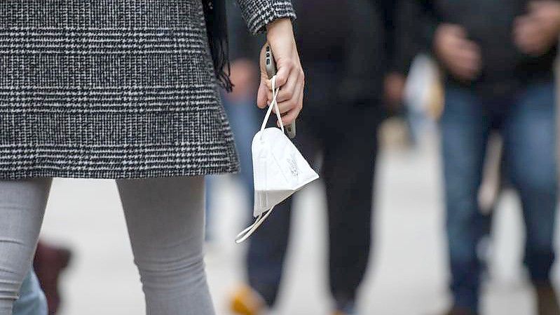 Eine Frau trägt am Nachmittag auf der Frankfurter Einkaufsmeile Zeil eine FFP-2-Maske in der Hand. (Archivbild). Foto: Frank Rumpenhorst/dpa