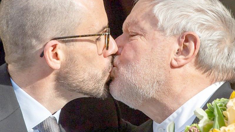 Der ehemalige Benediktiner-Mönch Anselm Bilgri (r) und sein Mann Markus küssen sich nach ihrer Trauung vor dem Münchner Standesamt in der Mandlstraße. Foto: Peter Kneffel/dpa