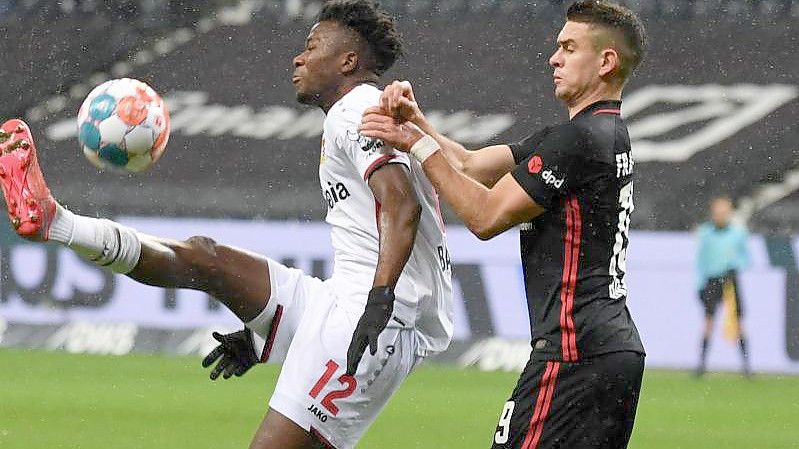 Frankfurts Borré (r) und Leverkusens Tapsoba kämpfen um den Ball. Foto: Arne Dedert/dpa