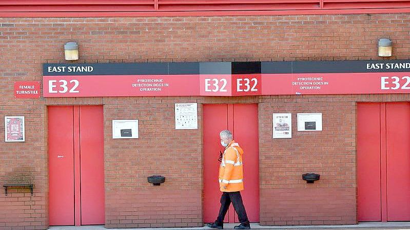 Ein Mitarbeiter geht an der Osttribüne des Old-Trafford-Stadions, der Heimstätte von Manchester United, vorbei. Foto: Anthony Devlin/PA Wire/dpa