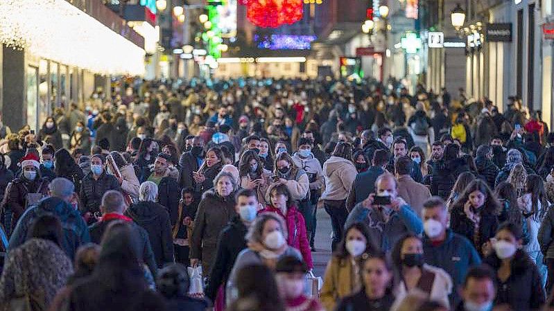 Menschen tragen Schutzmasken gehen durch die Innenstadt in Madrid. Foto: Bernat Armangue/AP/dpa