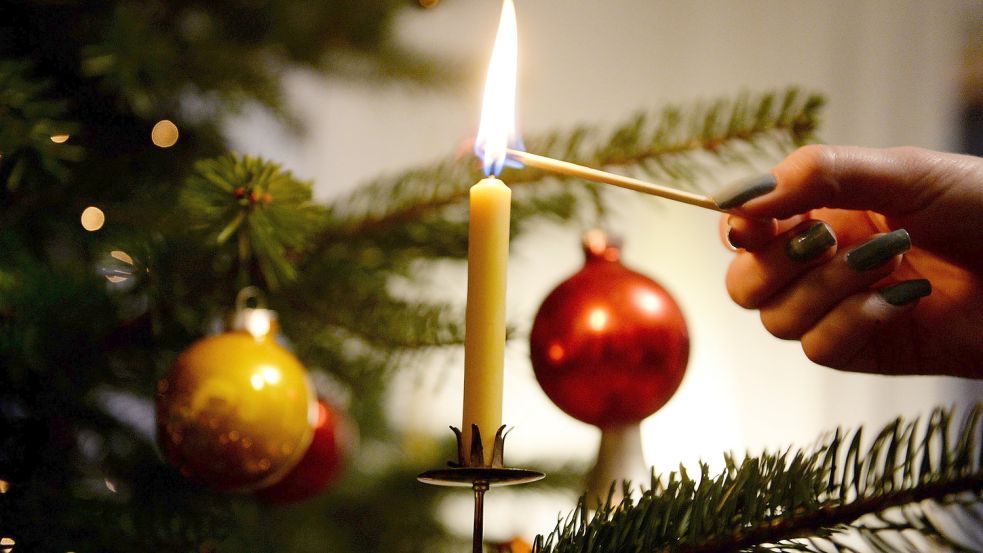 Eine Kerze am Weihnachtsbaum wird entzündet. Foto: DPA