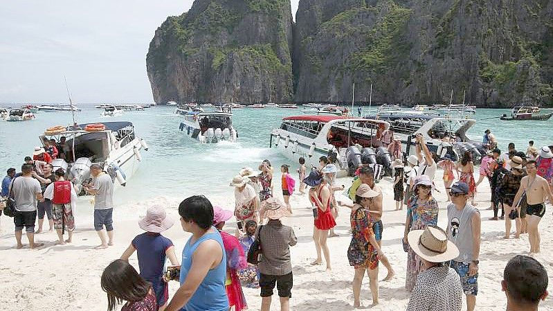 Touristen besuchen den Strand Maya Bay. Foto: Sakchai Lalit/AP/dpa