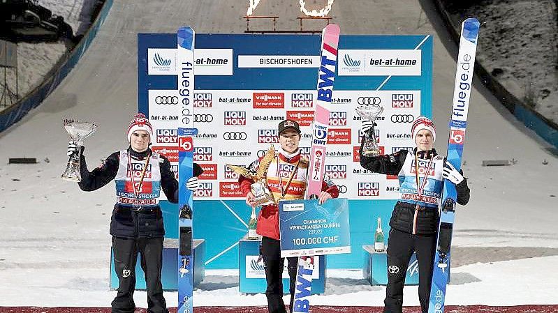 Ryoyu Kobayashi (M) jubelt mit dem Pokal für den Gesamtsieger, einem goldenen Adler, neben dem Gesamtzweiten Marius Lindvik (l) und dem Gesamtdritten Halvor Egner Granerud. Foto: Daniel Karmann/dpa