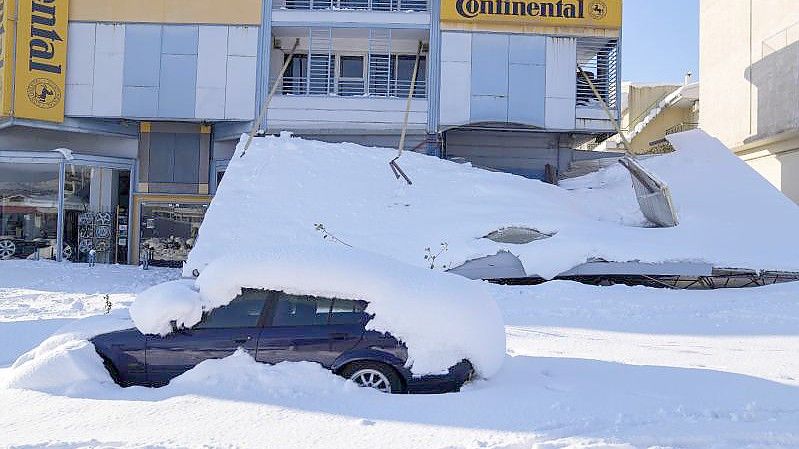 Ein schneebedecktes Auto steht vor einem beschädigten Gebäude. Über dem Großraum Athen waren ungewöhnlich starke Schneefälle niedergegangen. Foto: Thanassis Stavrakis/AP/dpa