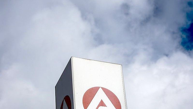 Wolken ziehen über ein Schild der Agentur für Arbeit und dem Berlin-Lichtenberg. Foto: Carsten Koall/dpa