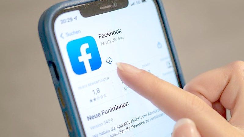 Eine Frau bedient die Facebook-App auf ihrem Handy. Foto: Mohssen Assanimoghaddam/dpa