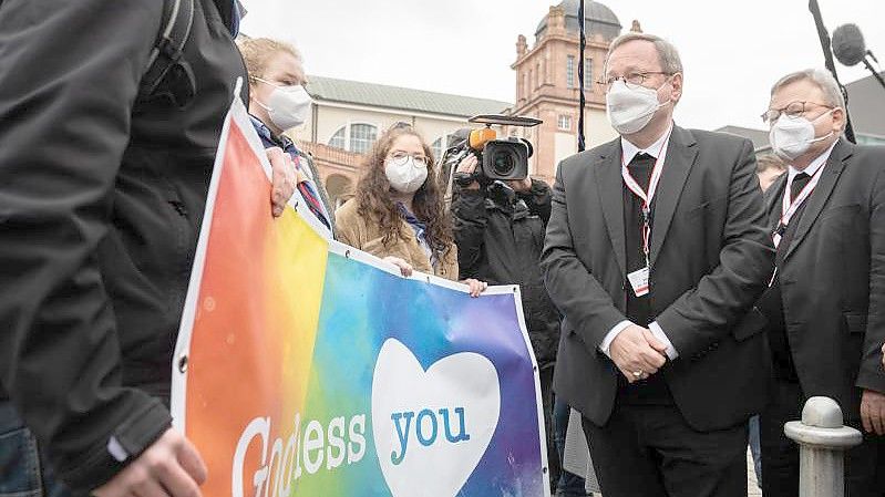 Der Vorsitzende der Deutschen Bischofskonferenz, Georg Bätzing, spricht vor der Synodalversammlung in Frankfurt mit Demonstranten, die eine vielfältigere Kirche fordern. Foto: Sebastian Gollnow/dpa