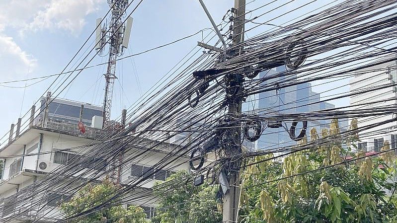 Strom- und Telefonleitungen werden in Thailand nicht unterirdisch verlegt, sondern spannen sich in massiven schwarzen Bündeln von Mast zu Mast. Foto: Carola Frentzen/dpa