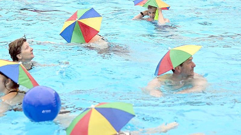 Schwimmen mit Regenschirm: Das Sonnenbad in Karlsruhe meldet sich aus der Winterpause zurück. Foto: Uli Deck/dpa