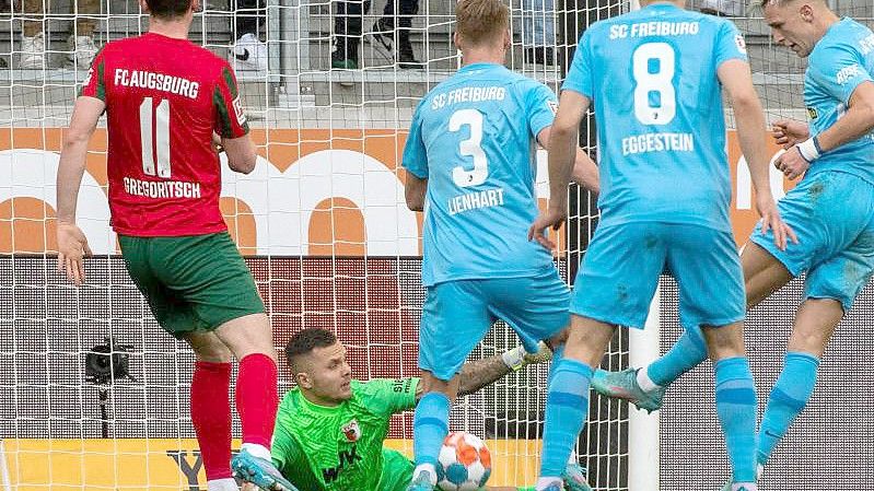 Augsburgs Michael Gregoritsch (l) und Torwart Rafal Gikiewicz können das 1:2 durch Freiburgs Nico Schlotterbeck (r) nicht verhindern. Foto: Stefan Puchner/dpa