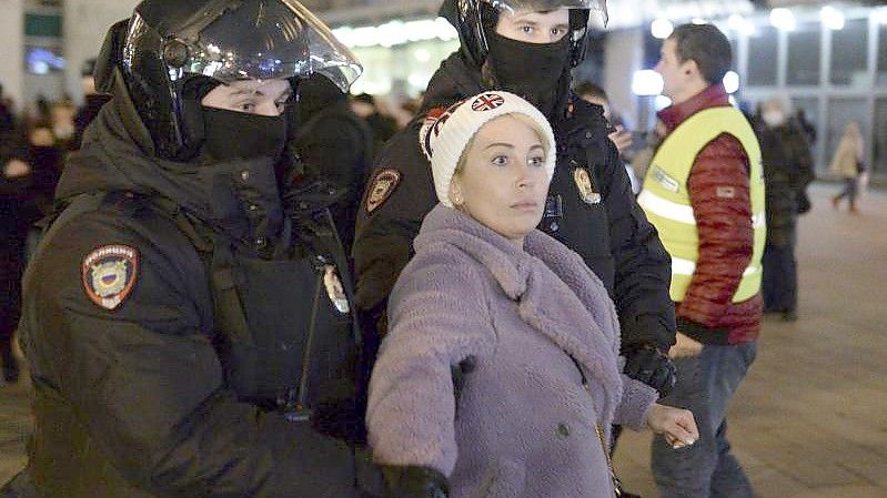 Zwei Polizisten nehmen eine Frau während einer Demonstration in Moskau gegen die russische Invasion in die Ukraine fest. Foto: Denis Kaminev/AP/dpa