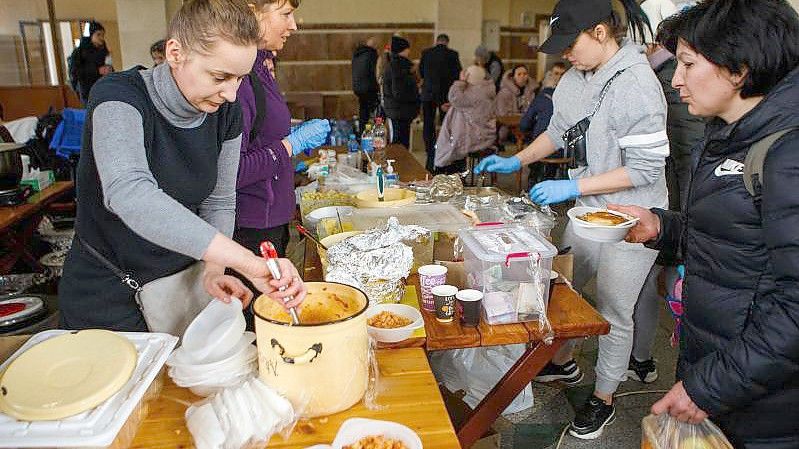 Menschen, die kurz zuvor evakuiert wurden, erhalten am Bahnhof von Uzhhorod in der Westukraine eine warme Mahlzeit. Foto: -/Ukrinform/dpa