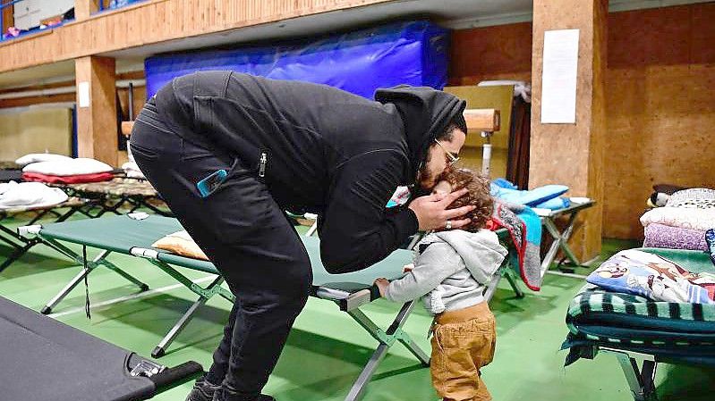 Ein aus der Ukraine geflüchteter Vater kümmert sich in einer ungarischen Notunterkunft um seine Tochter. Foto: Marton Monus/dpa