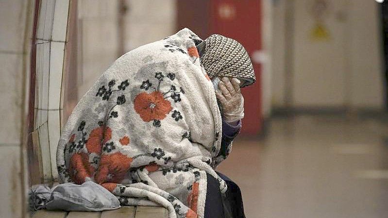 Viele U-Bahn-Stationen in Kiew wurden in Schutzräume umfunktioniert. Eine ältere Frau wartet eingewickelt in eine Decke auf das Ende des Luftalarms. Foto: Vadim Ghirda/AP/dpa