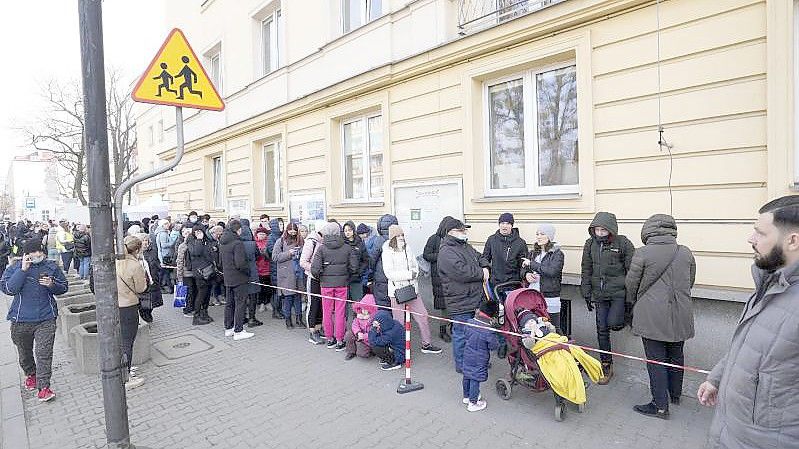 Aus der Ukraine geflüchtete Menschen stehen vor einer Meldestelle Schlange. Foto: Czarek Sokolowski/AP/dpa