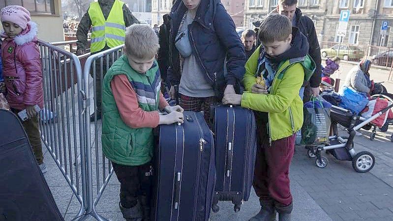 Ukrainische Flüchtlinge und ihre Kinder warten am Bahnhof im polnischen Przemysl. Foto: Sergei Grits/AP/dpa