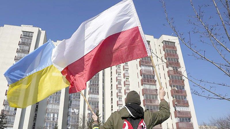 Ein Mann schwenkt während einer Demonstration in Warschau die ukrainische und die polnische Flagge vor einem Gebäude, in dem russische Diplomaten untergebracht sind. Foto: Czarek Sokolowski/AP/dpa