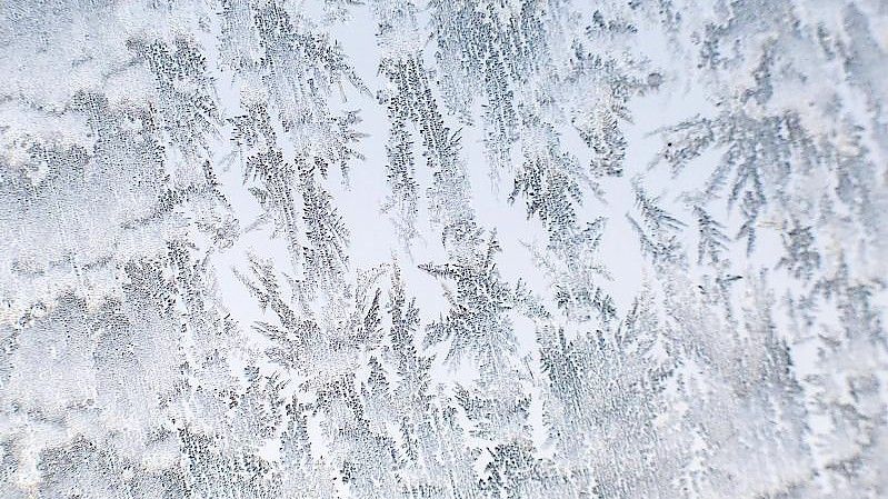 Eiskristalle zeichnen auf einer Autoscheibe ab. Foto: Julian Stratenschulte/dpa