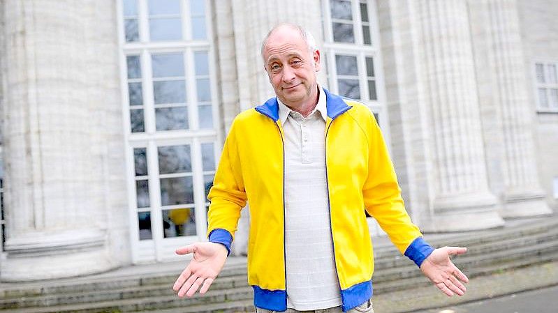 Der deutsch-französische Kabarettist und Satiriker Emmanuel Peterfalvi alias Alfons zeigt sich mit seiner nun aus Solidarität für die Ukraine gelb-blauen Trainingsjacke. Foto: Jonas Walzberg/dpa