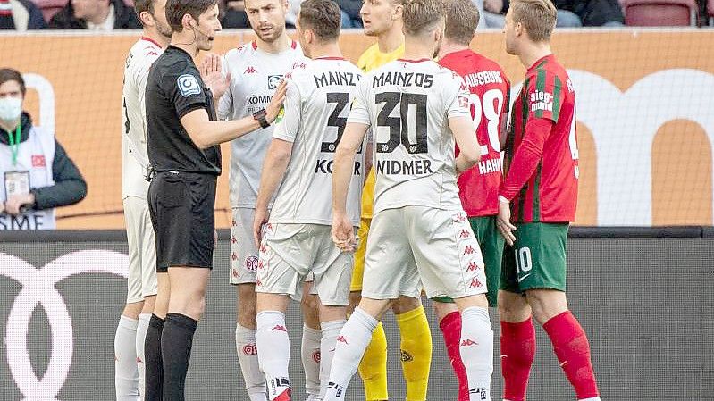 Schiedsrichter Matthias Jöllenbeck (l) spricht mit den Spielern. Foto: Matthias Balk/dpa