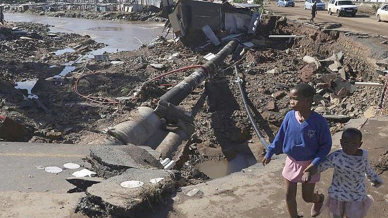 Kinder auf einer durch Überschwemmungen beschädigten Straße in Durban. Foto: Str/AP/dpa