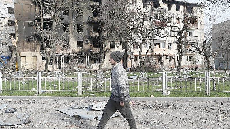 Ein Mann geht in der Nähe eines durch Beschuss zerstörten Wohnhauses in Mariupol. Foto: -/victor/XinHua/dpa