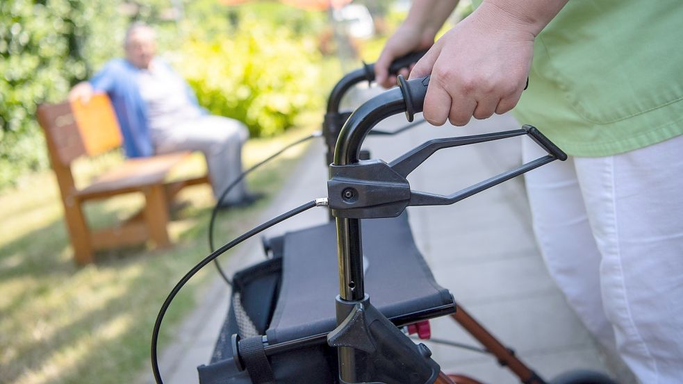 Eine Pflegefachkraft schiebt im Freien einen Rollator. Foto: DPA