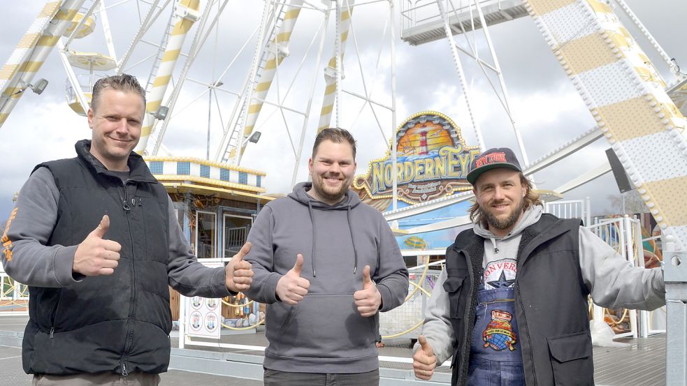 Die ostfriesischen Schausteller Timo von Halle, Dennis Eden und Stefano Glöss vor dem neuen Riesenrad „Nordern-Eye“. Foto: Aiko Recke