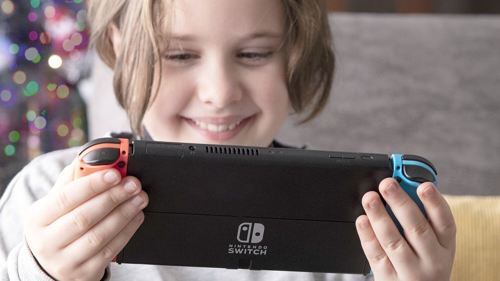 Girl playing Nintendo Switch sitting on a sofa at livingroom. Empty copy space for Edi Foto: IMAGO/Pond5 Images