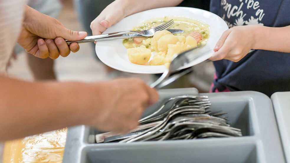 Ein Teller mit einem warmen Essen wird an ein Kind überreicht. Das Symbolbild zeigt eine typische Mensaszene. Foto: DPA