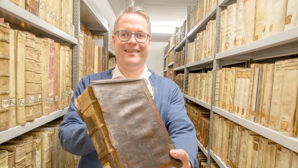 Dr. Heiko Suhr zeigt ein beschädigtes Buch aus der Bibliothek von Christoph Friedrich von Derschau. Foto: Ostfriesische Landschaft