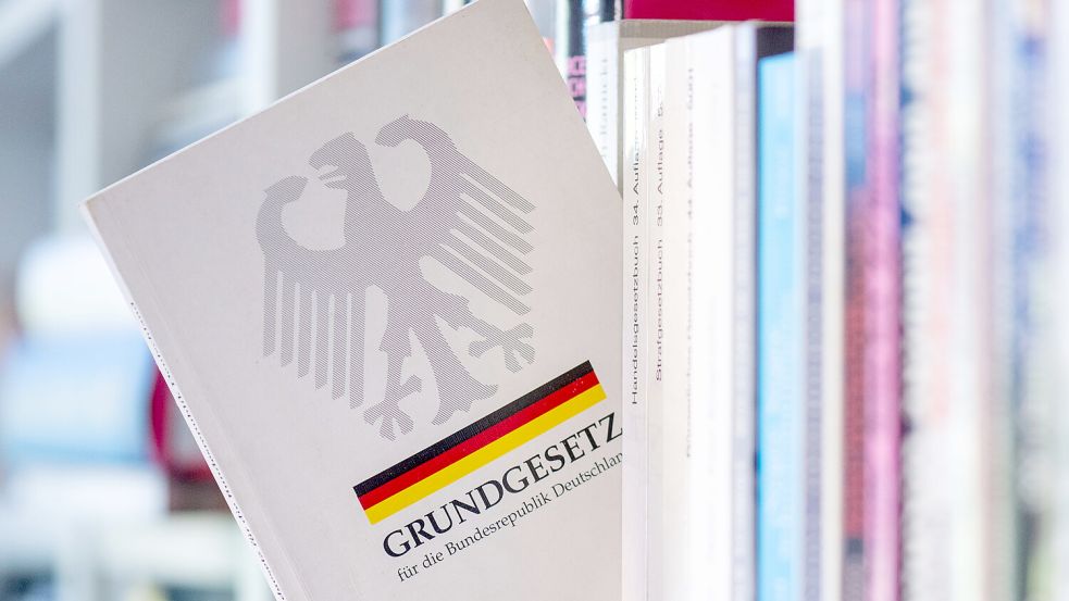 Ein Grundgesetz steckt in einem Bücherregal. Das Grundgesetz der Bundesrepublik feiert in diesem Jahr seinen 75. Geburtstag. Es wurde am 23. Mai 1949 erlassen. Foto: DPA