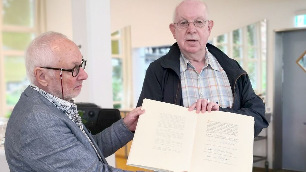 Norbert Niederhagen (rechts) hatte ein Faksimile der ersten Ausgabe des Grundgesetzes mit zur Diskussion gebracht und zeigte es zusammen mit Jörg Köhler vom Verein Aurich zeigt Gesicht. Foto: Karin Böhmer