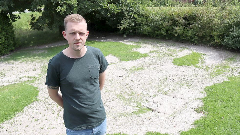 Kevin Wienekamp steht auf seinem Grundstück neben dem Sichtungsschacht des OOWV (rechts). Aus diesem sprudelte ihm zufolge am Freitagabend Abwasser aus der Kanalisation auf den Rasen. Die Toilettenpapierreste sind noch da. Foto: Karin Böhmer