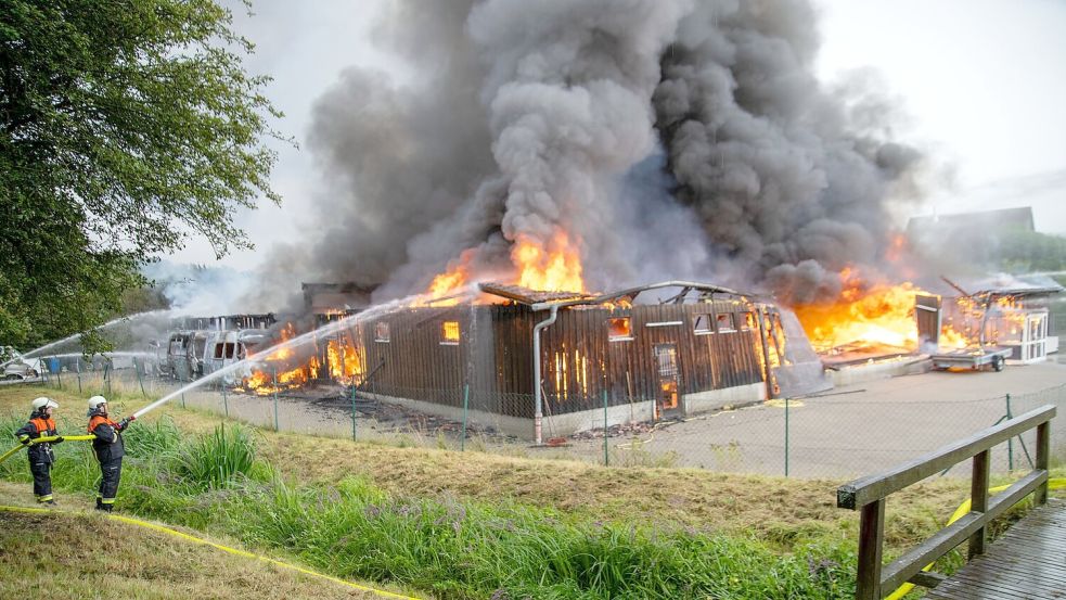 Einsatzkräfte löschen eine brennende Lagerhalle mit Fahrzeugen in Untermerzbach Foto: Pia Bayer/dpa