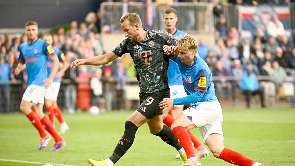 Bayerns Harry Kane (l-r) behauptet den Ball gegen Kiels Finn Porath. Foto: Gregor Fischer/dpa