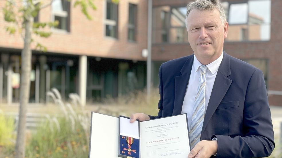 Der Ihlower Bürgermeister Arno Ulrichs zeigt die Urkunde und das Bundesverdienstkreuz am Bande. Foto: Christin Wetzel