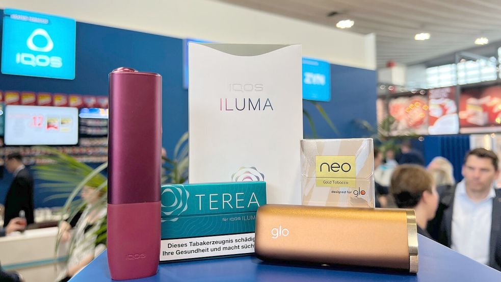 Ein Tabakerhitzer der Marke Iqos vom Hersteller Philip Morris und ein dazugehöriges Päckchen Tabaksticks der Marke Terea sowie das Konkurrenzprodukt Glo (mit Neo-Tabaksticks) des Herstellers BAT liegen bei der Fachmesse Intertabac in einer Messehalle. Foto: Wolf von Dewitz/dpa