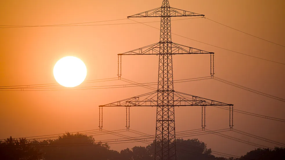 Die Sonne geht hinter einer Hochspannungsleitung auf. Foto: DPA