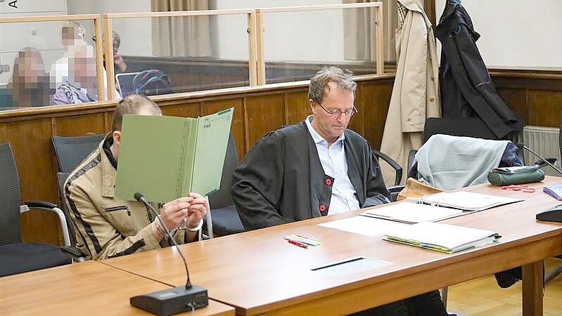 Der Angeklagte schützt sein Gesicht mit einem Aktendeckel. Neben ihm sitzt Verteidiger Folkert Adler. Fotos: Banik