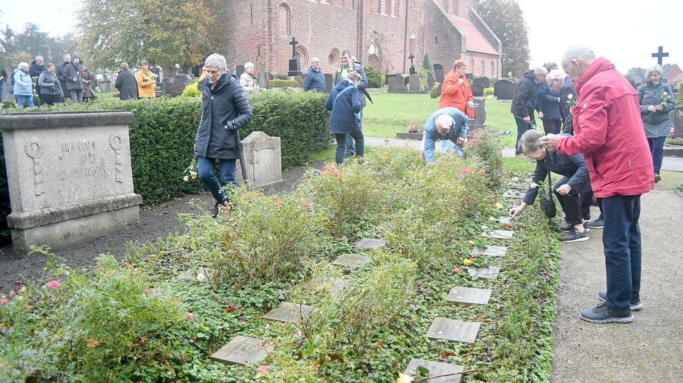 Auf dem neben der Kirche liegenden Gräberfeld legten Teilnehmer der Gedenkveranstaltung Rosen nieder. Foto: Gerd-Arnold Ubben