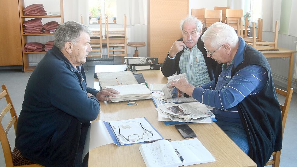 Onno Ringering (links, Herold Folkers (Mitte) und Otto Sinnen schauen sich im Gemeindehaus Bangstede, dem Übungsraum des Chores, alte Unterlagen über den Chor an. Die Zukunft des Chores sehen sie eher skeptisch. Foto: Gerd-Arnold Ubben