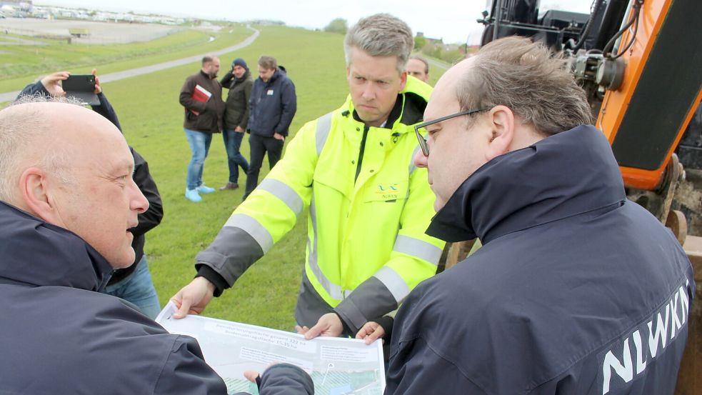 Niedersachsens Umweltminister Christian Meyer (Grüne, rechts im Bild) ließ sich im April 2024 von Mitarbeitern des NLWKN auf dem Deich in Harlesiel die Pläne für die Erhöhung erklären. Foto: Oltmanns